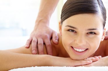 Smiling female looking at camera during luxurious procedure of massage